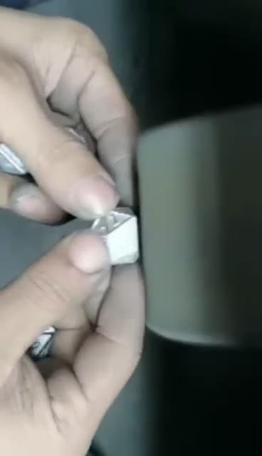 Hands holding a metal component against a polishing wheel